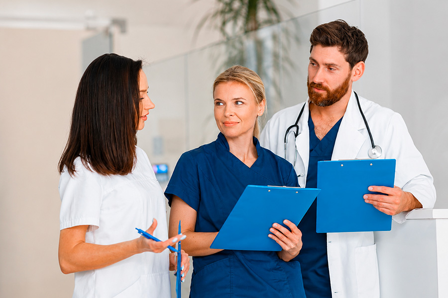 Tre operatori sanitari che discutono insieme tenendo in mano delle cartelle cliniche