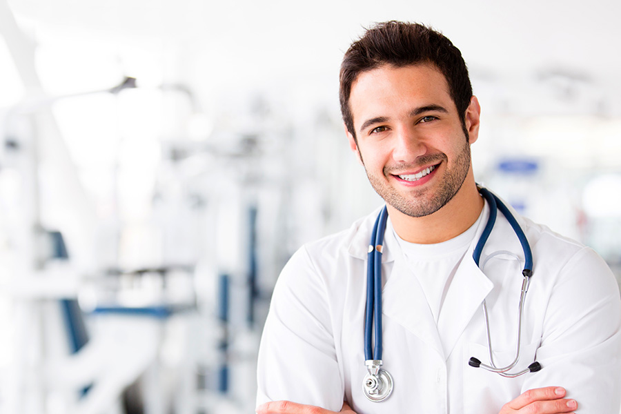 Medico competente con camice bianco e stetoscopio, sorridente, in un ambiente sanitario luminoso
